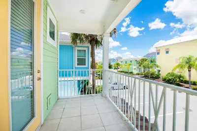 a balcony with a blue house and palm trees at Luxurious Cottage Near Disney With Margaritaville Resort & Island H2O Access - 8000Dr in Orlando