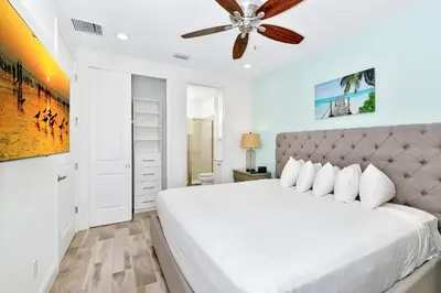 a bedroom with a white bed with a ceiling fan at The Tipsy Turtle Cottage With Private Pool Near Disney With Margaritaville Resort & Island H2O Access - 8012St in Orlando