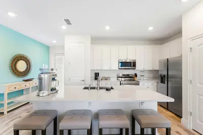 a kitchen with white cabinets and a large island with stools at Bright And Cozy Villa Near Disney With Margaritaville Resort & Island H2O Access - 3053Cs in Orlando