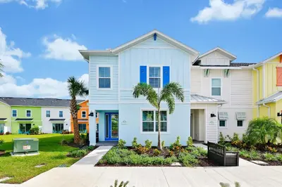 a white house with palm trees in a neighborhood at Lovely Villa Near Disney With Margaritaville Resort & Island H20 Waterpark Access - 2956Or in Orlando