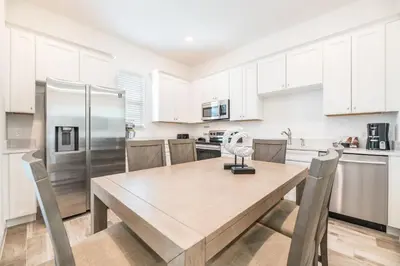 a kitchen with a wooden table and a refrigerator at Cozy Cottage With Private Pool Near Disney With Margaritaville Resort & Island H2O Access - 8041Kd in Orlando