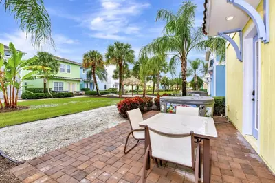 a patio with a table and chairs and palm trees at Lively Cottage With Hot Tub Near Disney With Margaritaville Resort & Island H2O Access - 8030Su in Orlando