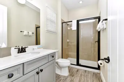 a white bathroom with a toilet and a sink at Lively Cottage With Hot Tub Near Disney With Margaritaville Resort & Island H2O Access - 8030Su in Orlando