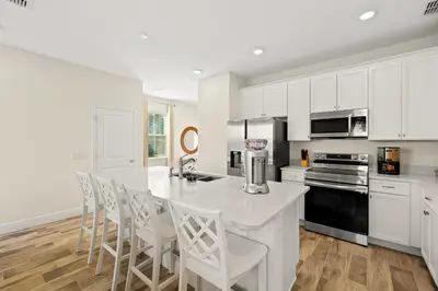 a kitchen with white cabinets and a white table and chairs at Tropical Villa Near Disney With Margaritaville Resort & Island H20 Waterpark Access - 2945Cs in Orlando