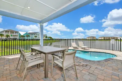 a patio with a table and chairs and a pool at Beautiful Waterfront Cottage With Private Pool Near Disney With Margaritaville Resort & Island H2O Access - 3024Ph in Orlando