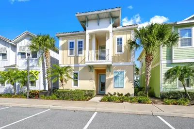 a house with palm trees in front of a street at Orange Creamsickle Cottage Near Disney With Margaritaville Resort & Island H20 Waterpark Access - 2980Sr in Orlando