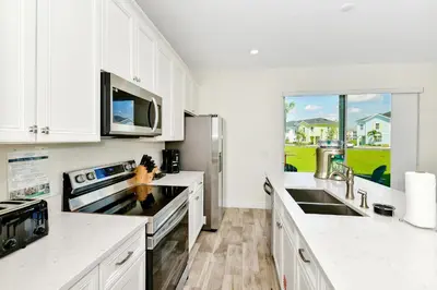 a kitchen with white cabinets and a large window at Glimmering Blue Villa Near Disney With Margaritaville Resort & Island H20 Waterpark Access - 3016Cs in Orlando