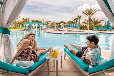 a man and woman sitting on lounge chairs by a pool at Relaxing Villa Near Disney With Margaritaville Resort & Island H20 Waterpark Access - 2992Cs in Orlando