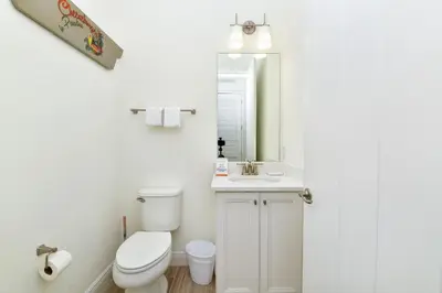 a bathroom with a toilet and a sink and a mirror at Breezy Green Cottage With Private Hot Tub Near Disney With Margaritaville Resort & Island H2O Access - 3055Pi in Orlando