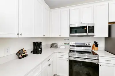a white kitchen with white cabinets and a microwave at Ocean Blue Villa Near Disney With Margaritaville Resort & Island H20 Waterpark Access - 3101Cs in Orlando