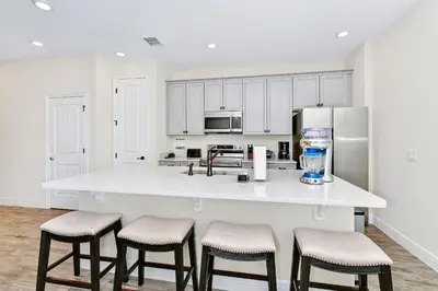 a kitchen with white cabinets and a counter with stools at Cozy Villa Near Disney With Margaritaville Resort & Island H20 Waterpark Access - 2976Or in Orlando