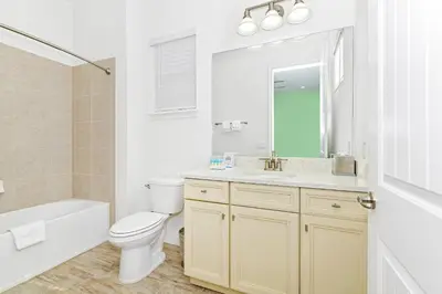 a white bathroom with a toilet and a sink at Cozy Cottage With Private Pool Near Disney With Margaritaville Resort & Island H2O Access - 8028Kd in Orlando