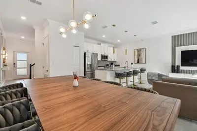 a dining room and living room with a wooden table at Storey Lake - Piscina privativa Cama King 4BD/3BA in Kissimmee