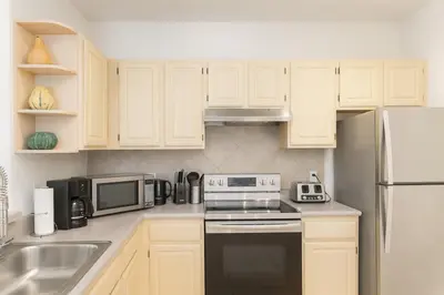 a kitchen with white cabinets and a stove and microwave at Conforto e Espaço: Apt de 2Q e 2B em Legacy Dunes in Kissimmee