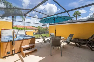 a patio with a table and an umbrella and a grill at Cozy 2Bd Spa & Jacuzzi Close to Disney at Encantada 3029 in Kissimmee