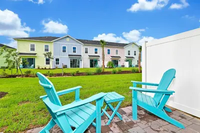 two blue chairs sitting on a patio in front of a house at Tropical Villa Near Disney With Margaritaville Resort & Island H20 Waterpark Access - 3180Cs in Orlando