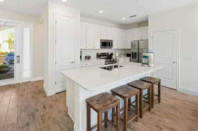 a kitchen with white cabinets and a counter with stools at Beautiful Villa Near Disney With Margaritaville Resort & Island H20 Waterpark Access - 2917Cs in Orlando