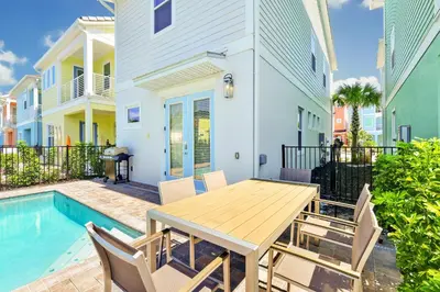 a dining table and chairs next to a pool at White Sand Cottage With Private Pool Near Disney With Margaritaville Resort & Island H2O Access - 8023Kd in Orlando