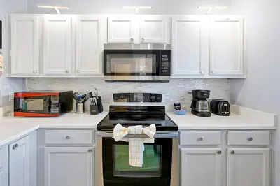 a kitchen with white cabinets and a stove top oven at Encantada Resort: Pool, Gym, Clubhouse, Near Disney in Kissimmee