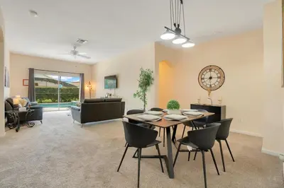 a living room with a table and chairs and a clock at Relaxing Retreat in the Windsor Palms Resort in Kissimmee