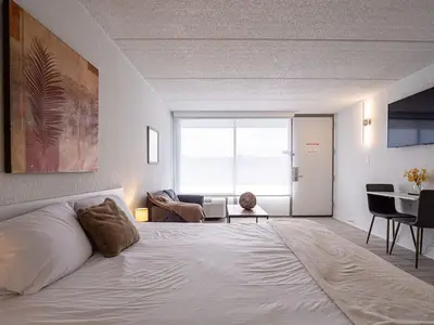 a bedroom with a large white bed and a living room at Lovely 1BR Suite Minutes to Disney With Lake view in Vineland