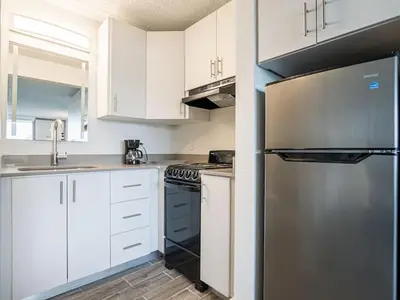 a kitchen with white cabinets and a stainless steel refrigerator at Elegant 1BR Haven in Orlando & 5 minutes to Disney in Vineland