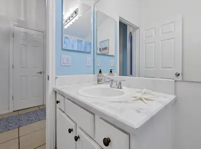 a white bathroom with a sink and a mirror at 6BD - Pool, BBQ & Movie Theater - 10 Mins to Disney in Kissimmee