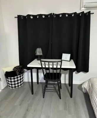 a table and a chair in front of a black curtain at The Sanford Foodie Guest House in Sanford