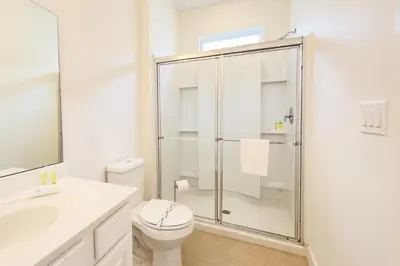 a white bathroom with a shower and a toilet at 2612 LunaPi Villa 7Bd Private Pool and Family Room in Kissimmee