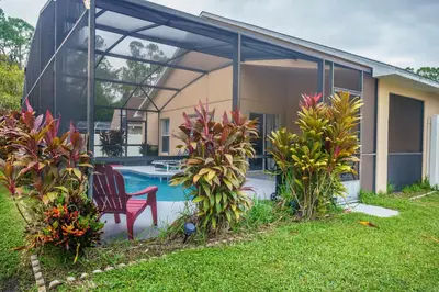 a house with a pool and a chair in the yard at 4 Bed Villa - Eagle Pointe - Kissimmee in Kissimmee