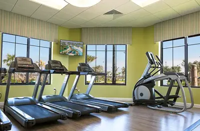 a gym with two tread machines in a room with windows at Bright and Modern 4BR Home,Pool,Slides,By Disney in Kissimmee