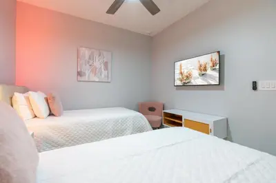 a bedroom with two beds and a tv on the wall at New Home 8 Bedrooms At Bella Vida in Kissimmee