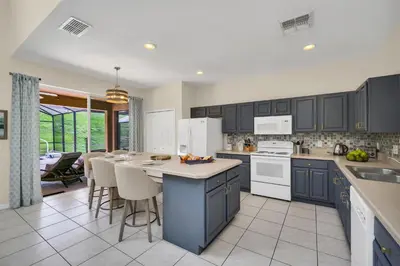 a kitchen with blue cabinets and white appliances at Family Villa with Private Pool Game Room & Themed Rooms in Kissimmee