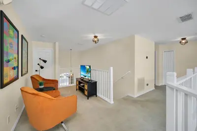a living room with an orange chair and a tv at Family Villa with Private Pool Game Room & Themed Rooms in Kissimmee