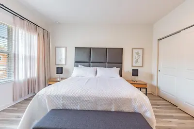 a white bedroom with a large bed and two tables at 2 Suítes, Jacuzzi priv. perto da DISNEY in Kissimmee