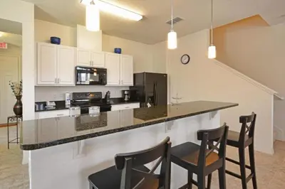 a kitchen with a bar with chairs and a counter top at Casa 4Q c/ Piscina Priv. e Vista Lago in Kissimmee