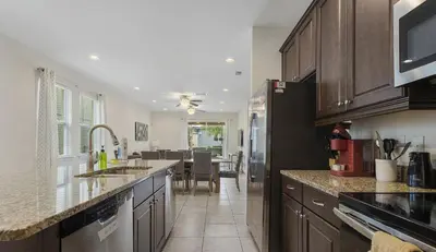 a kitchen with wooden cabinets and a dining room at Casa c/ Piscina, Sala de Jogos e 6 Suítes in Orlando