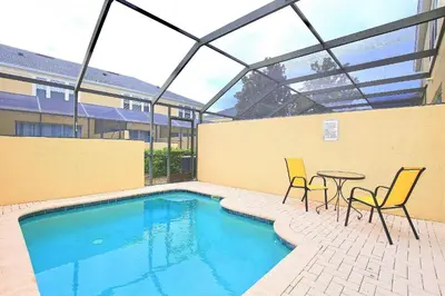 a swimming pool with two chairs and a table next to a building at 7660 - 3Q/3B Casa em Resort *10min DISNEY* in Orlando