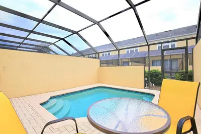 a patio with a pool and a table and chairs at 7660 - 3Q/3B Casa em Resort *10min DISNEY* in Orlando