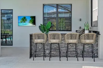 a table with four rattan chairs in front of a building at Gorgeous Paradiso Mansion-Poolgame Roomtheater-3 in Orlando