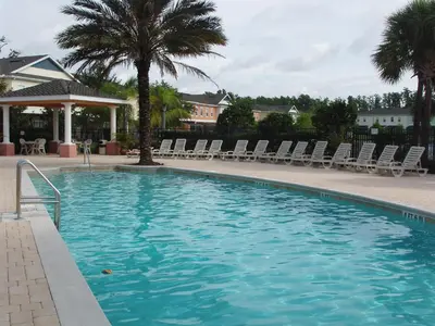 a large swimming pool with chairs and a palm tree at Four Bedroom Villa in Coral Cay in Kissimmee
