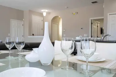 a table with wine glasses and a vase on it at 4BR Lakefront - Themed Rooms - Pool & BBQ! in Kissimmee