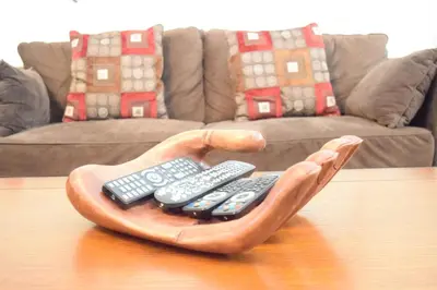 a hand holding three remote controls on a table at 2551 Oneida Grantham! in Kissimmee
