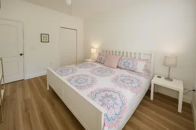 a white bedroom with a bed with a pink and blue blanket at Casa p/ 4 · Perto da Disney · Cozinha completa in Kissimmee
