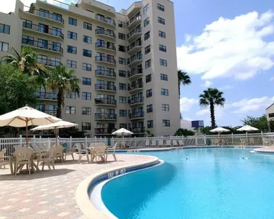 a swimming pool with chairs and umbrellas in front of a building at 6165 Carrier Drive 1001 in Orlando