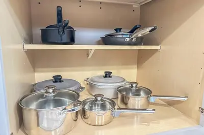 a group of pots and pans on shelves in a kitchen at EPIC STYLISh retreat With Free water park near Disney in Kissimmee