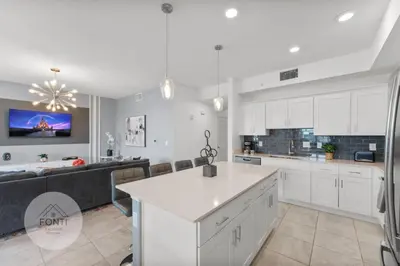 a kitchen with white cabinets and a living room at Modern Storey Lake Resort Disney Orlando 3191-307 in Kissimmee