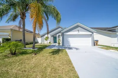 a house with palm trees in front of a driveway at Vacation Oasis Home with Private Pool and Grill 8615 in Kissimmee