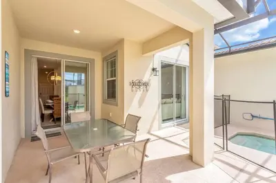 a patio with a glass table and chairs and a swimming pool at Storey Lake Resort Townhouse near Disney Orlando 4847 in Kissimmee
