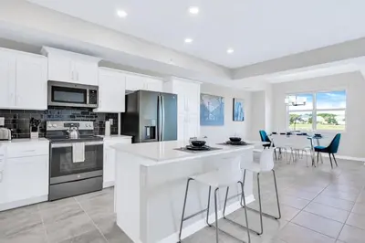 a kitchen with white cabinets and a table and chairs at Modern Storey Lake Resort Disney Orlando 3171-107 in Kissimmee
